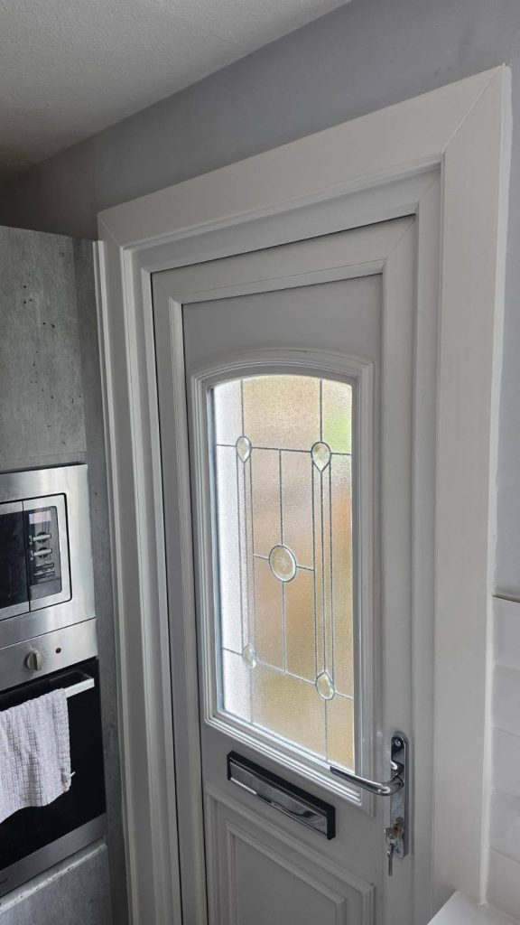 After: new white back door with a decorative bevelled glass panel, fitted in a kitchen