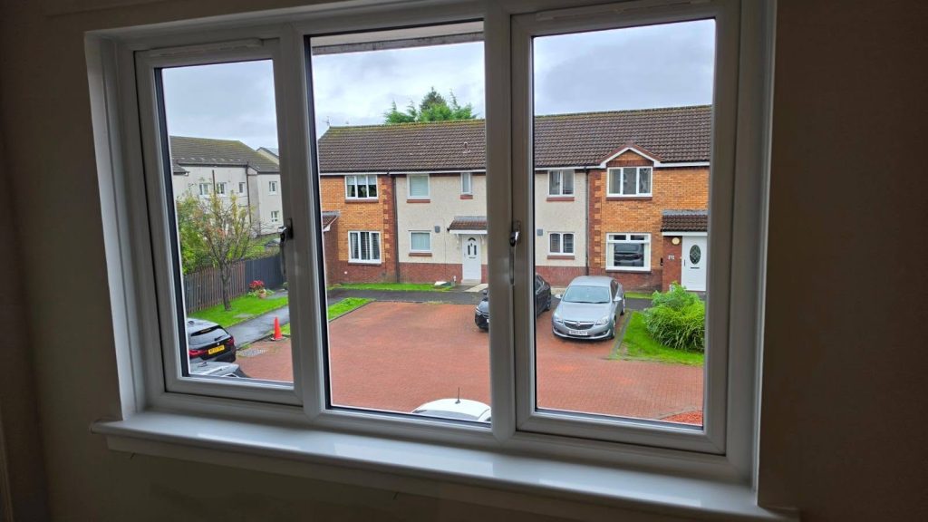 New white three-pane Rehau uPVC window in Yoker, seen from inside, looking out over the street